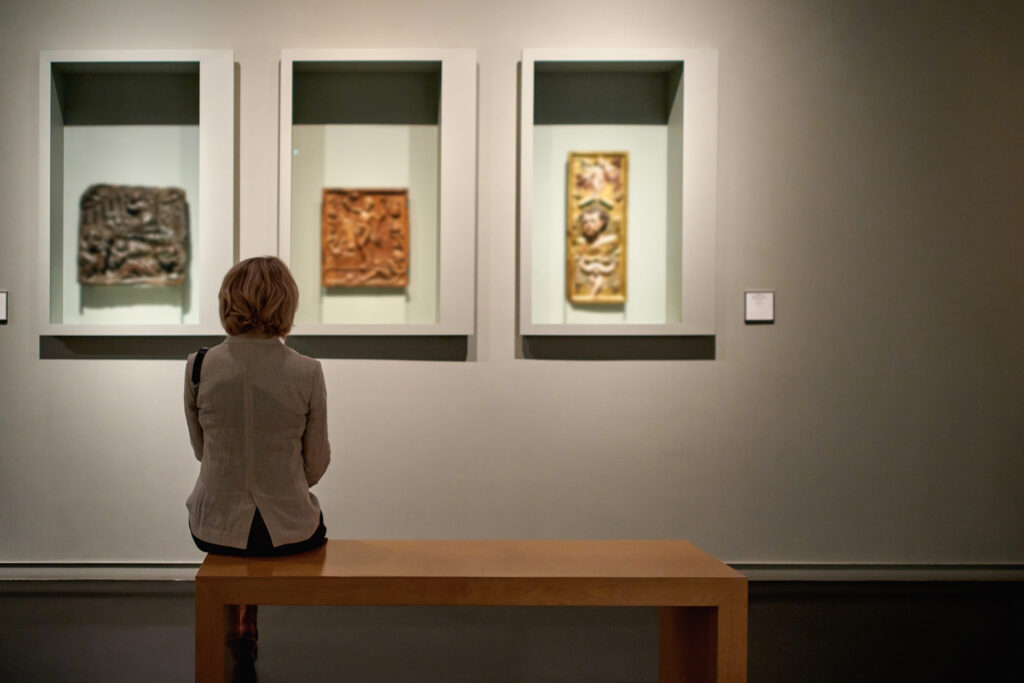 rear view of woman sitting in an art gallery in front of colorful paintings